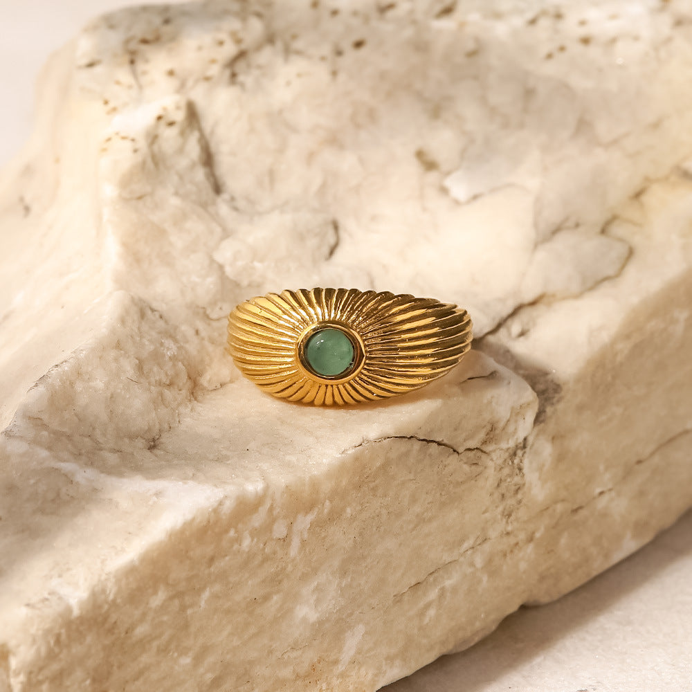 18K Gold Plated Green Stone Sun Ring displayed on satin fabric, featuring a sun-shaped design with a green stone.